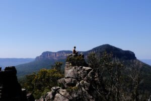 At Ruined Castle, man sitting zen like on large rock column with Mt. Solitary imposing in the background