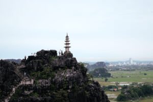 An ancient Vietnamese temple in the foreground with hills and city shadowing in the background