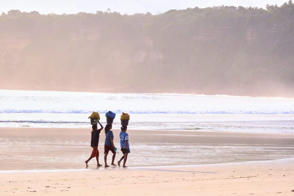 3 ladies walking back along the beach to their village after a successful harvest