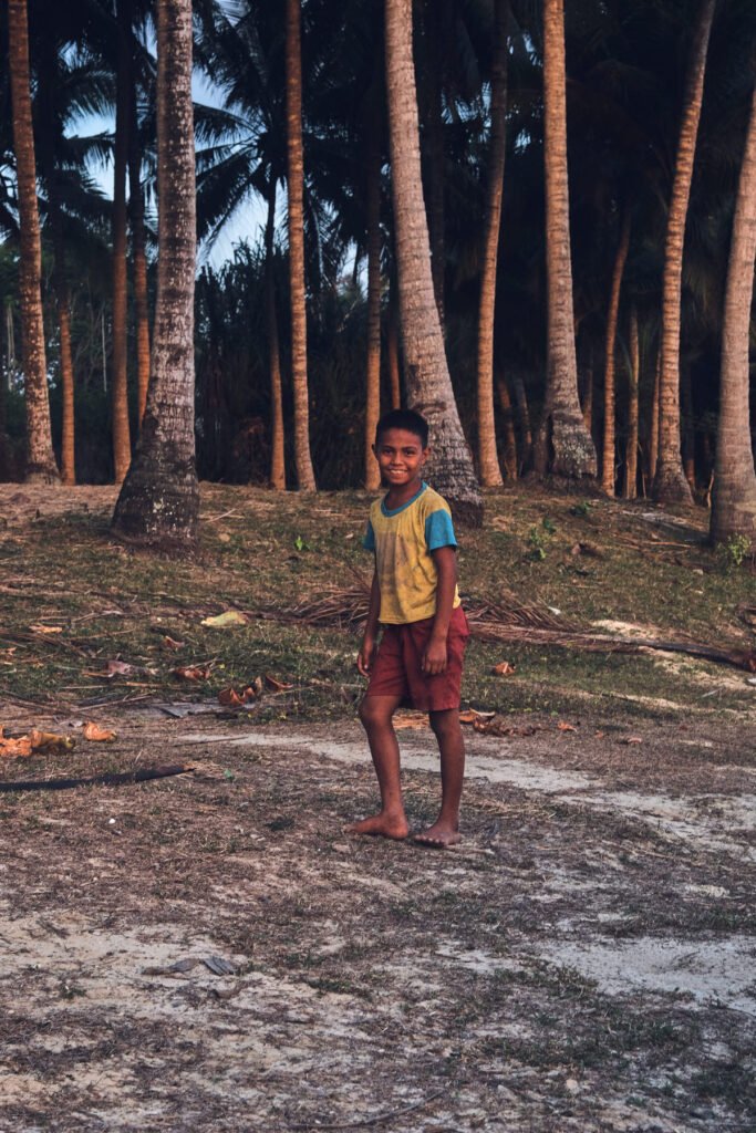 A wandering boy next to the dirt patch we parked our car on. The trunks of big trees loom in the background