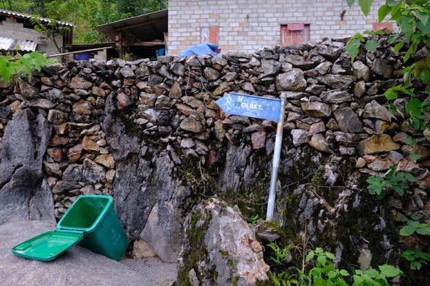 A blue sign at the village, indicating to follow the path left