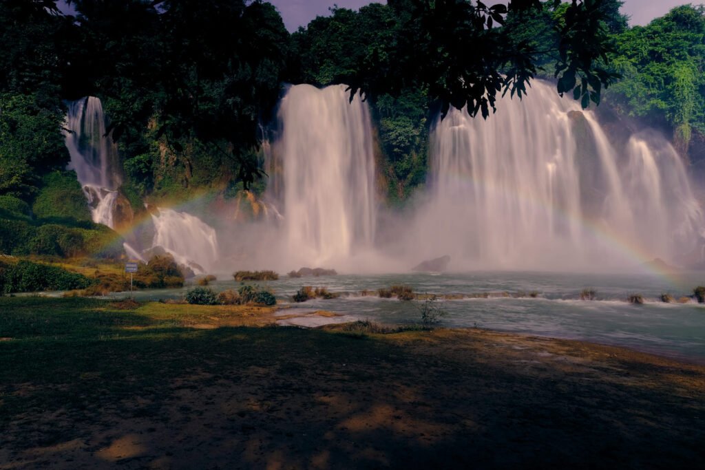 The cascades at Ban Gioc waterfall, Vietnam. A half rainbow appears in front of the fast flowing cascades.