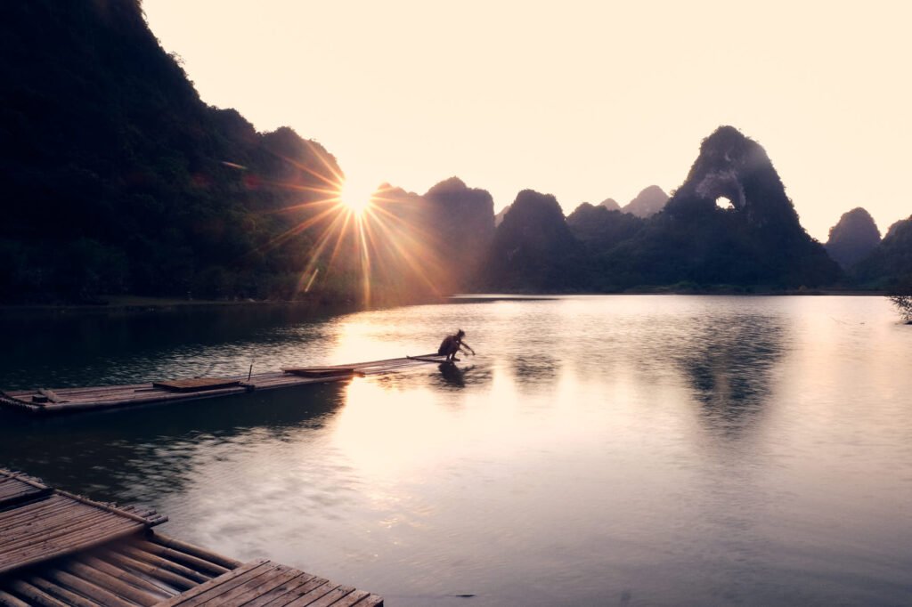 A man squats on a docked raft at the lakes edge of God's Eye Mountain to wash his hands.