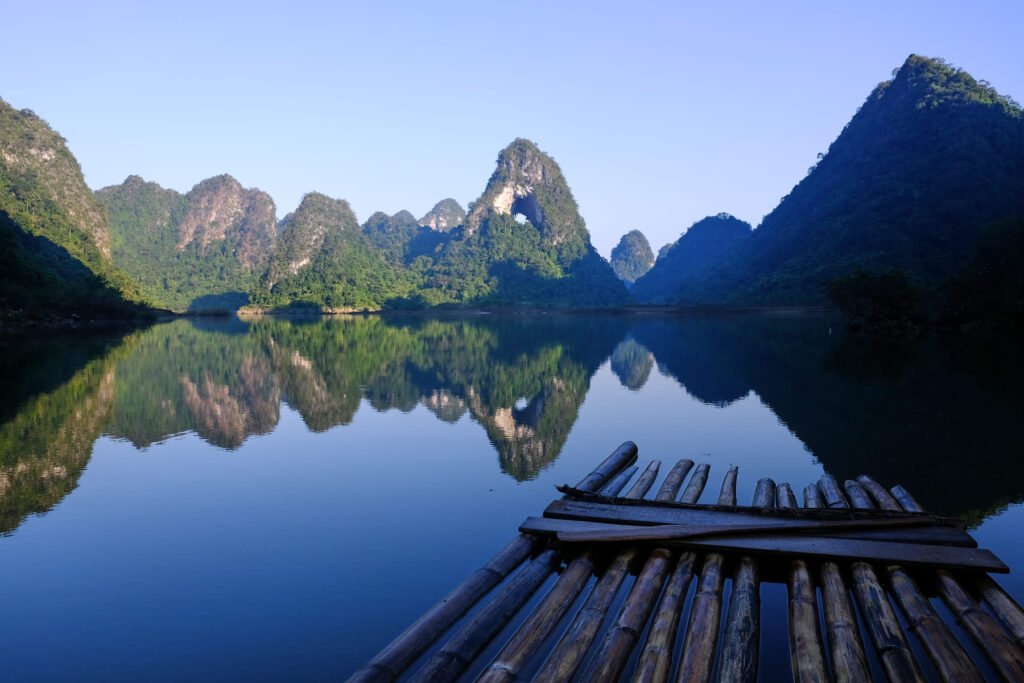 A traditional raft floats on the calm waters, with God's Eye in the background reflecting a mirror image.