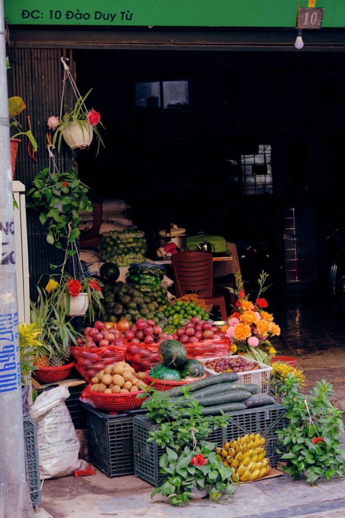 A seemingly unoccupied fruit shop in the streets of Hanoi. The fruits are arranged neatly in an array of colours.