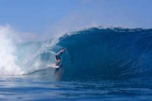 A surfer in a perfect barrel @Desert Point Indonesia, giving the peace sign to his friends